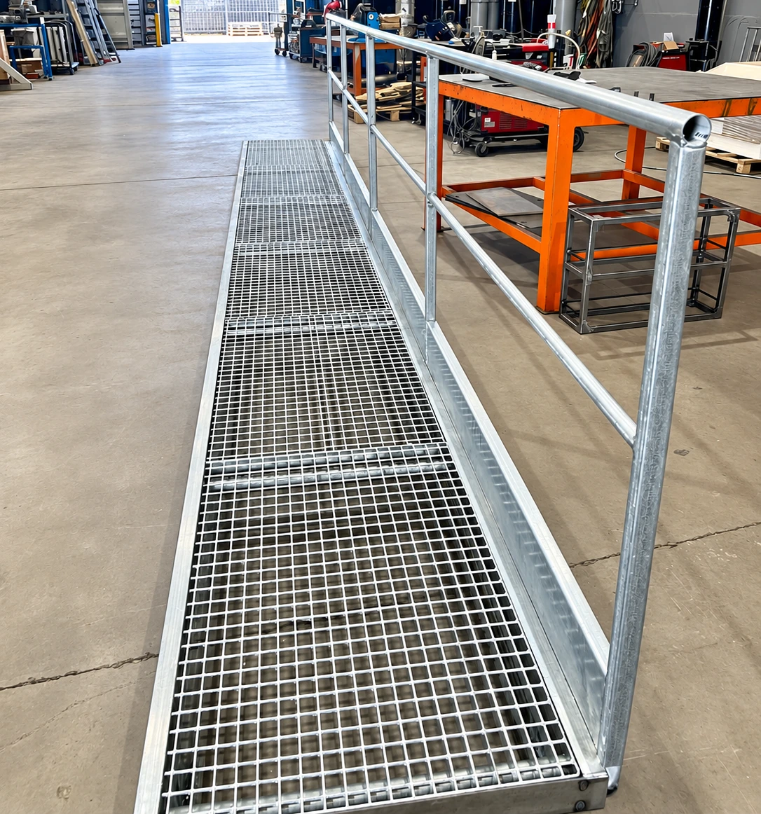 Pasarela de rejilla galvanizada con barandilla lateral en el taller