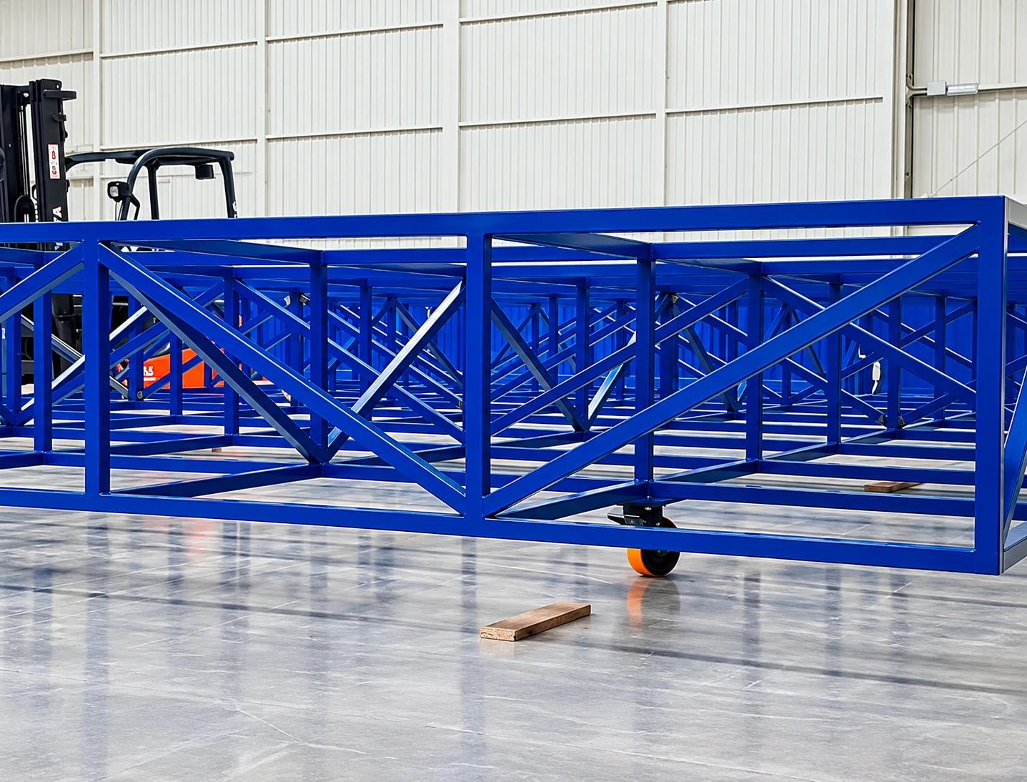 Bastidor metálico azul con refuerzos diagonales y ruedas en el taller